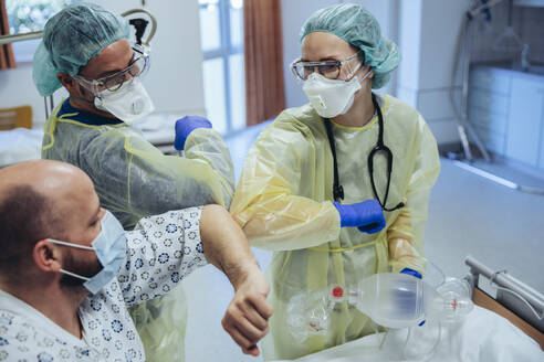 Ärzte stoßen mit dem Ellbogen an einen geheilten Patienten in der Notaufnahme eines Krankenhauses - MFF05351