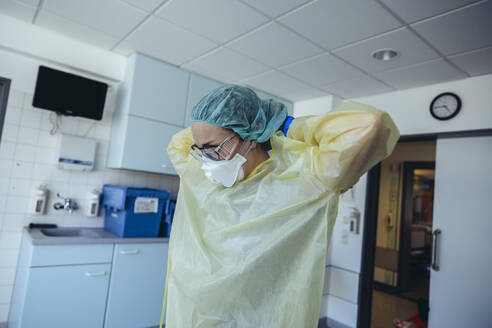 Doctor putting on personal protective equipment in hospital - MFF05354