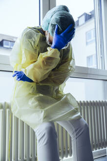 Verzweifelter Arzt trägt persönliche Schutzausrüstung im Krankenhaus - MFF05355