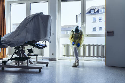 Exhausted doctor wearing personal protective equipment in hospital - MFF05356