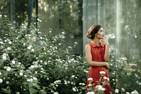 Nachdenkliche junge Frau im städtischen Garten stehend, lizenzfreies Stockfoto