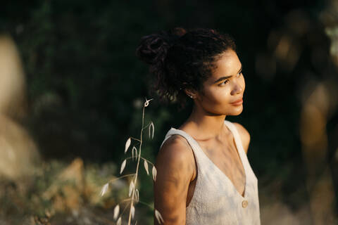 Portrait of young woman in nature watching sunset stock photo