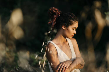 Porträt einer jungen Frau in der Natur, die den Sonnenuntergang genießt - TCEF00393