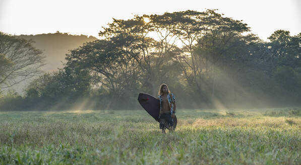 Junger Surfer auf dem Weg zum Strand bei Sonnenaufgang, Costa Rica - AMUF00032