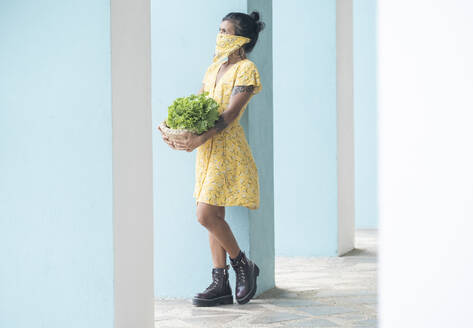 Frau mit Mundtuch hält Korb mit Salat und frischen Früchten - AMUF00038
