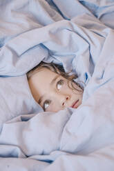 Porträt eines ängstlichen Mädchens, das unter einer Decke liegt - ERRF02960