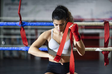 Junge Frau bindet sich im Boxclub einen Verband um die Hand - JSMF01493