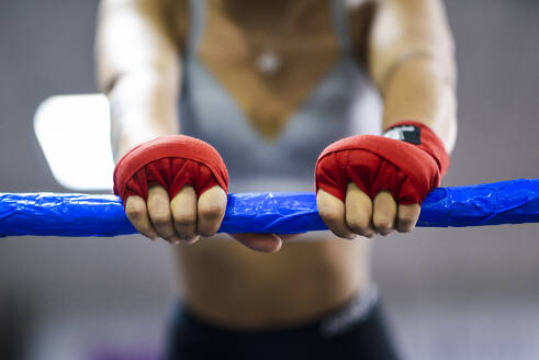 Nahaufnahme einer weiblichen Boxerin im Boxring, die sich auf ein Seil stützt - JSMF01497