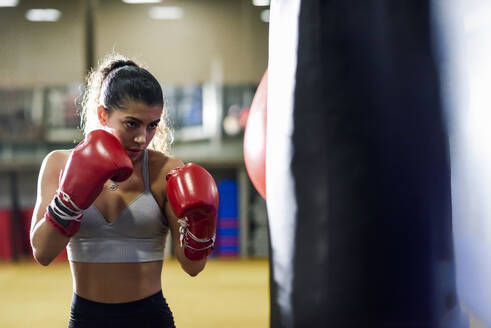 Weiblicher Boxer beim Training am Sandsack im Fitnessstudio - JSMF01504