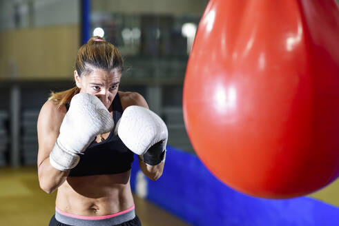 Weiblicher Boxer beim Training am Sandsack im Fitnessstudio - JSMF01506