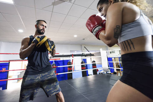 Weibliche Boxerin beim Sparring mit ihrem Trainer im Fitnessstudio - JSMF01508