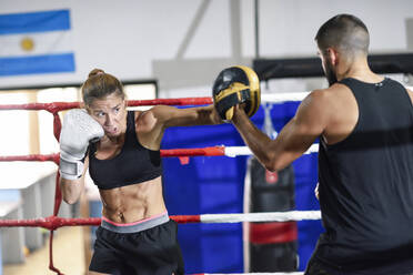 Female boxer sparring with her coach in gym - JSMF01514