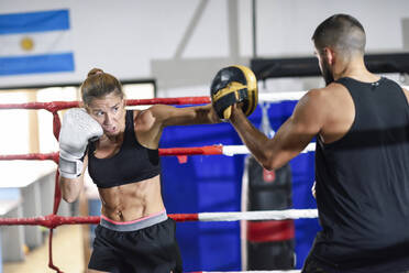 Weibliche Boxerin beim Sparring mit ihrem Trainer im Fitnessstudio - JSMF01514