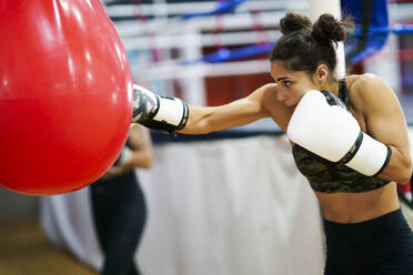 Weiblicher Boxer beim Training am Sandsack im Fitnessstudio - JSMF01527