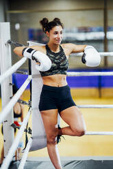 Athletische Boxerin im Boxring, die sich vor dem Kampf auf ein Seil stützt und sich konzentriert - JSMF01529