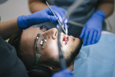 Man wearing headphones receiving dental treatment - DGOF00613