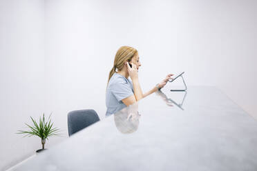 Receptionist at reception desk of a medical practice using headset and digital device - DGOF00641