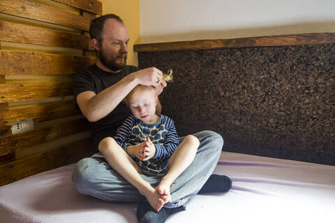 Vater bindet seiner kleinen Tochter die Haare, lizenzfreies Stockfoto
