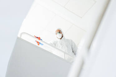 Reinigungspersonal im Anzug reinigt Geländer mit Desinfektionsmittel - CJMF00285