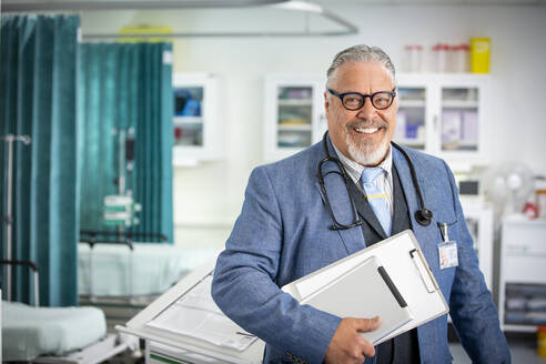 Porträt selbstbewusster männlicher Oberarzt bei der Visite im Krankenhaus - CAIF24907