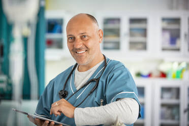 Porträt selbstbewusster männlicher Arzt mit digitalem Tablet im Krankenhaus - CAIF24908