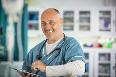 Portrait confident male doctor with digital tablet in hospital - CAIF24908