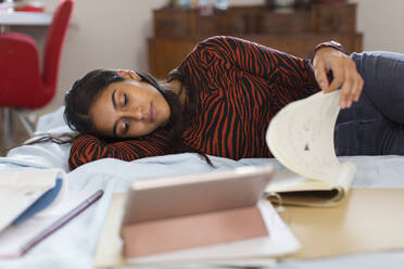 Jugendliches Mädchen studiert, liegt auf dem Bett und liest ein Buch - CAIF24922
