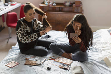 Teenager-Mädchen tragen Make-up auf und bürsten sich die Haare im Bett - CAIF24923