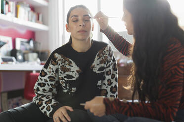 Teenager-Mädchen trägt Lidschatten-Make-up auf die Augen von Freunden auf - CAIF24926
