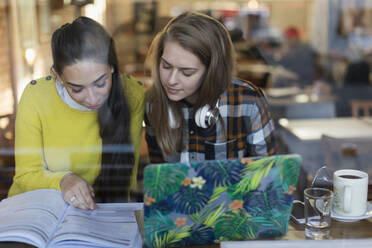 Junge Studentinnen studieren im Fenster eines Cafés - CAIF24931
