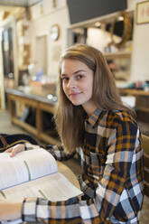 Porträt einer selbstbewussten jungen Studentin, die in einem Café studiert - CAIF24941