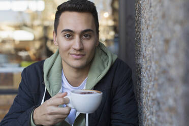 Porträt selbstbewusster junger Mann trinkt Cappuccino - CAIF24942