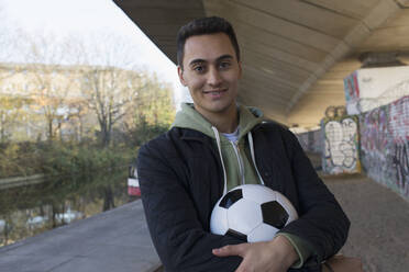 Porträt selbstbewusster junger Mann mit Fußball - CAIF24959