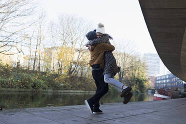 Happy young couple hugging along urban canal - CAIF24973