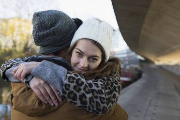 Porträt einer glücklichen jungen Frau, die ihren Freund umarmt - CAIF24974