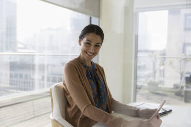 Portrait happy, confident businesswoman using digital tablet in conference room - CAIF24999
