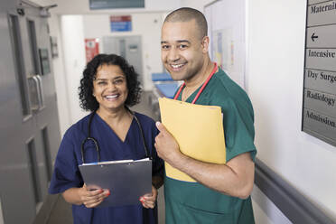 Porträt selbstbewusster Ärzte mit Krankenblatt bei der Visite im Krankenhauskorridor - CAIF25038