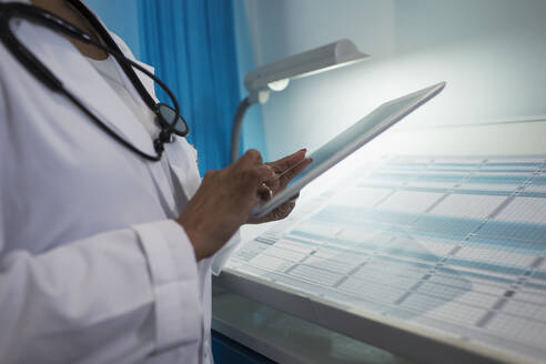 Nahaufnahme einer Ärztin, die ein digitales Tablet in einem Krankenhauszimmer benutzt - CAIF25056