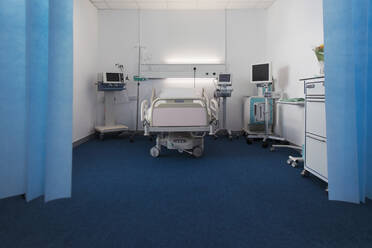 Leerstehendes Krankenhauszimmer mit Bett und medizinischen Geräten - CAIF25064