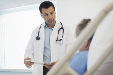 Arzt mit digitalem Tablet bei der Visite, Gespräch mit Patient im Krankenhausbett - CAIF25069