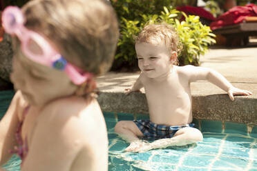 Porträt eines lächelnden kleinen Jungen, der im Swimmingpool sitzt, Koh Samui, Thailand - AUF00266