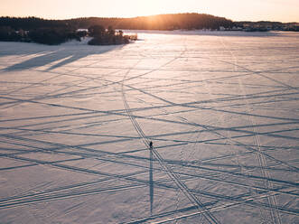 Luftaufnahme eines Mannes, der an der Kreuzung der Wege des winterlichen Ladogasees steht, Republik Karelien, Sortavala, Russland. - AAEF07247