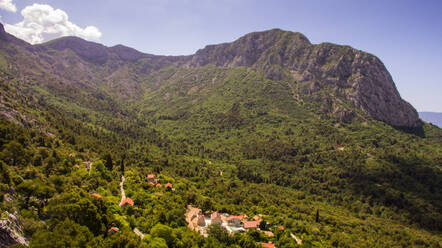 Luftaufnahme des alten Dorfes und der umliegenden Wälder und Berggipfel bei Zaostrog in Dalmatien, Kroatien. - AAEF07314