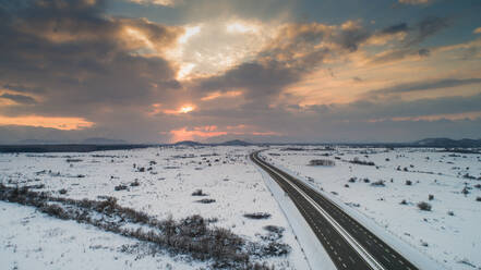 Luftaufnahme des winterlichen Sonnenuntergangs und des Schnees auf der A1, der Hauptautobahn in Kroatien, die die Städte Split und Zagreb verbindet, aufgenommen in Lika. - AAEF07455