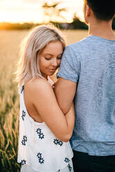 Smiling young couple standing in golden wheat field, hugging. - ISF23982