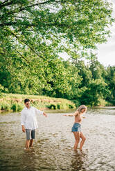 Junges Paar steht knöcheltief in einem Fluss. - ISF23994