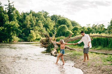 Junges Paar, das Hand in Hand an einem Flussufer spazieren geht. - ISF23997