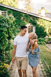 Young couple standing arm in arm outside cottage - ISF24011