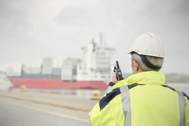 Dockmanager mit Walkie-Talkie bei der Überwachung eines Containerschiffs im Handelsdock - CAIF25079