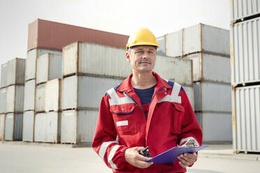 Porträt eines selbstbewussten Hafenarbeiters mit Klemmbrett und Walkie-Talkie in einer Werft - CAIF25103